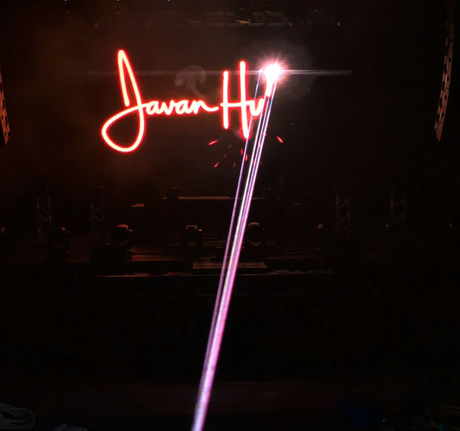 A red laser signature mid-draw on a real stage, beam and sparks visible